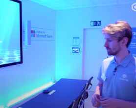 Q-SYS ペリフェラルを備えたMicrosoft Teams Signature Room を検査している男性のビデオ サムネイル