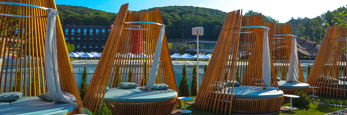 Resort style chairs in front of a large swimming area and a hotel